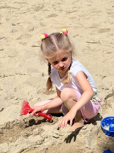 Mädchen spielt im Sand in der Sonne