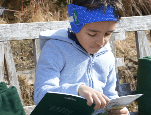 Kind mit Ohrenwickel liest ein Buch