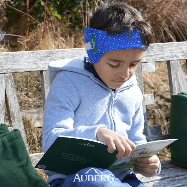 Kind mit Ohrenwickel liest ein Buch